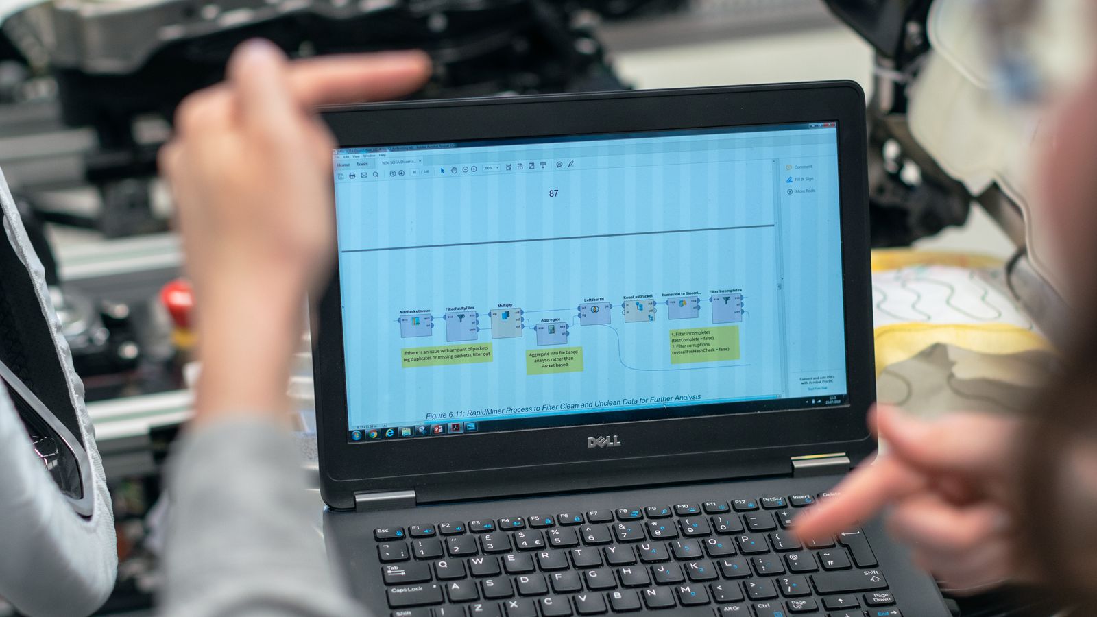 Engineers using a laptop to analyze data in an industrial workshop