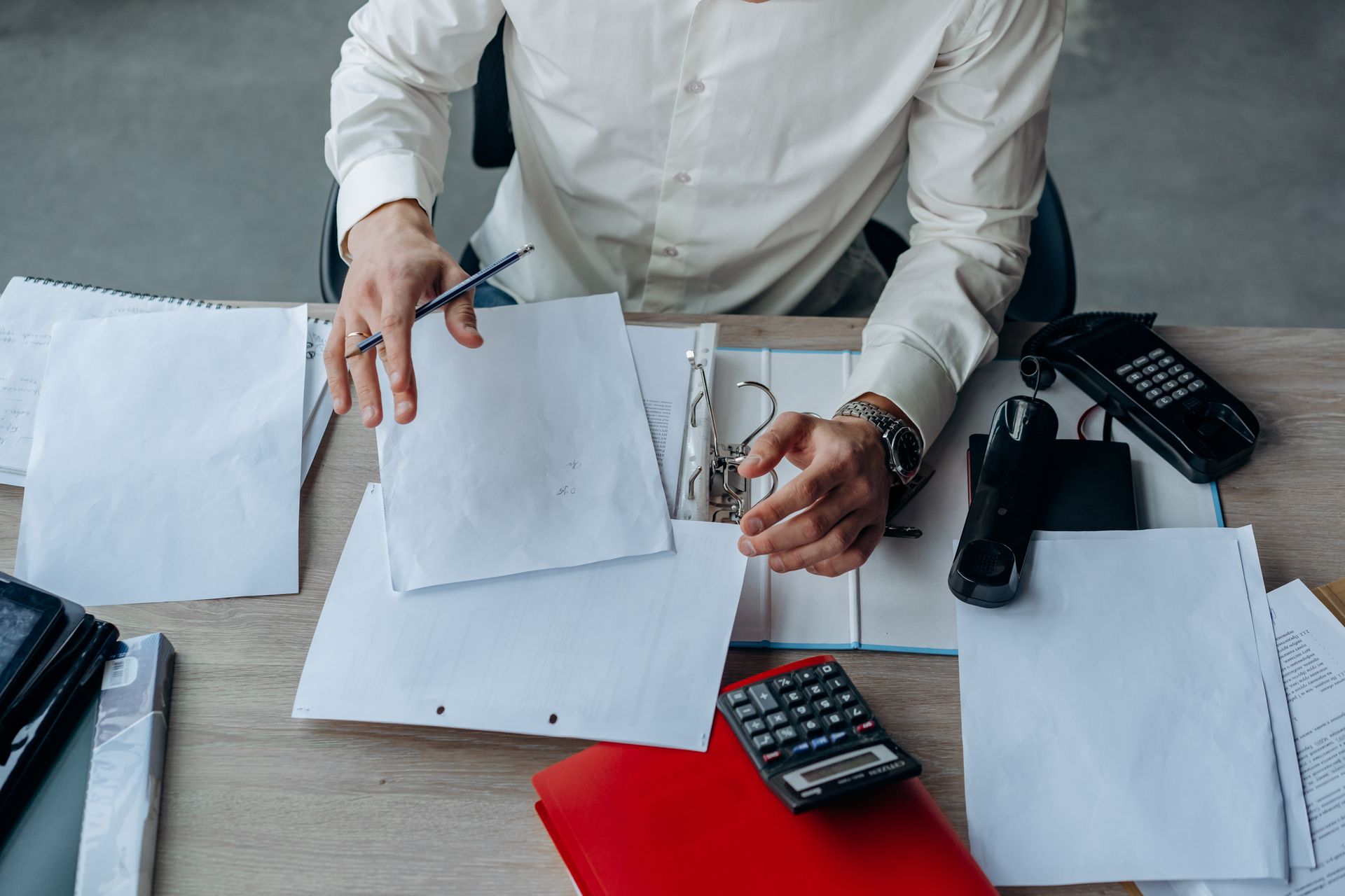 Business owner organizing bid documents at a busy office desk