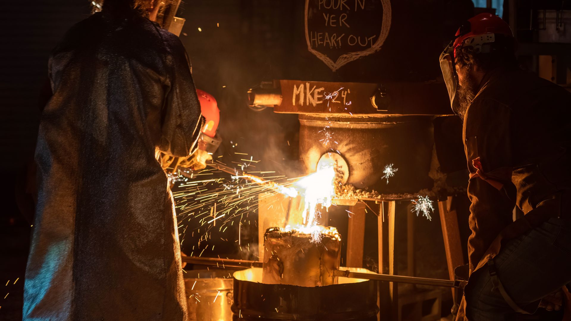 Workers pouring molten metal at a steel plant at night