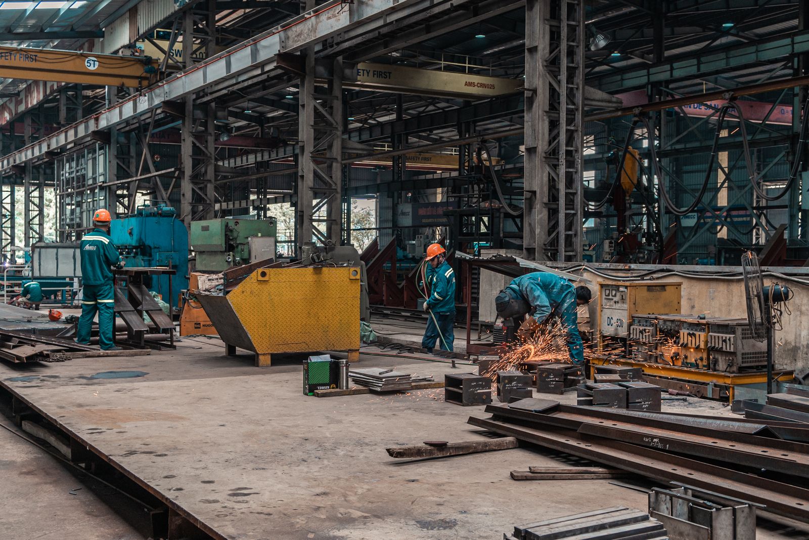 Workers on a factory floor with welding sparks