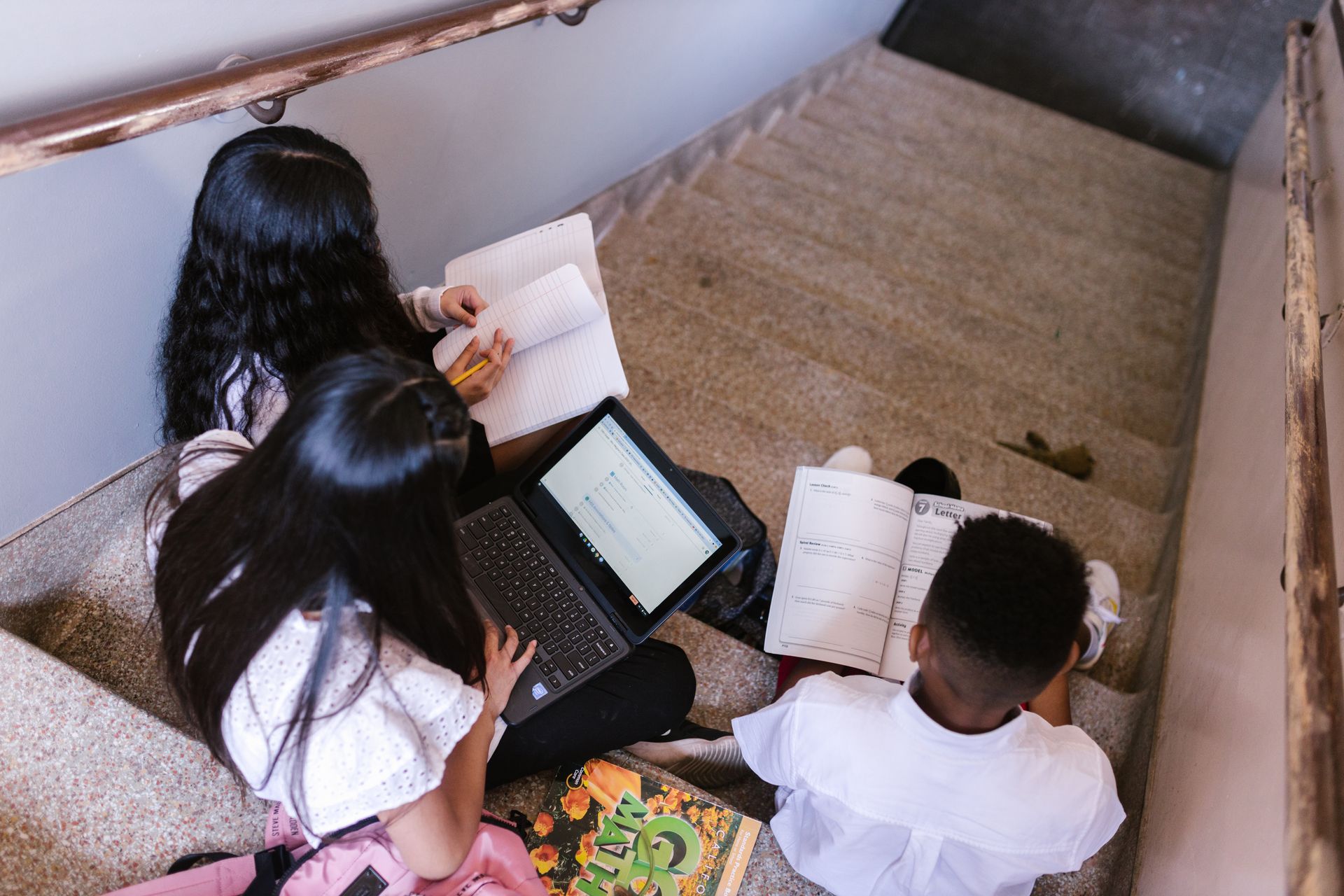 Students using laptops and notebooks together at school