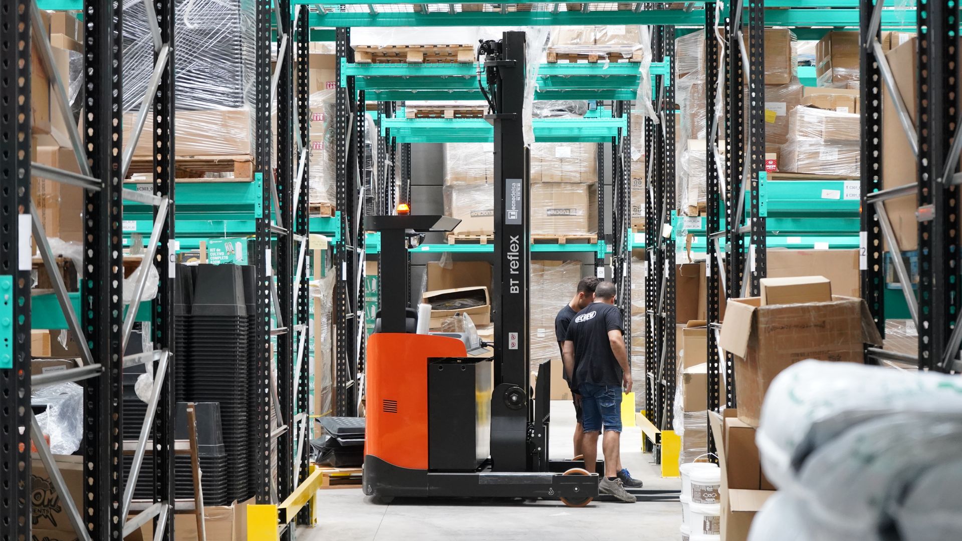 Workers and a forklift moving goods in a large warehouse